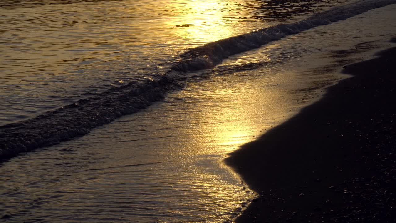 Calm ocean waves on beach, during sunset