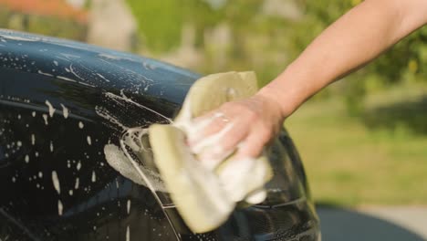 Manual-washing-of-a-black-car-headlight,-front-side-view