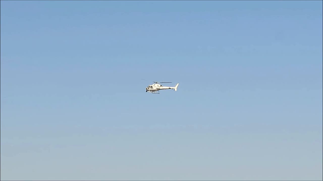 Helicopter in blue cloudless sky over Andalusian village, Spain