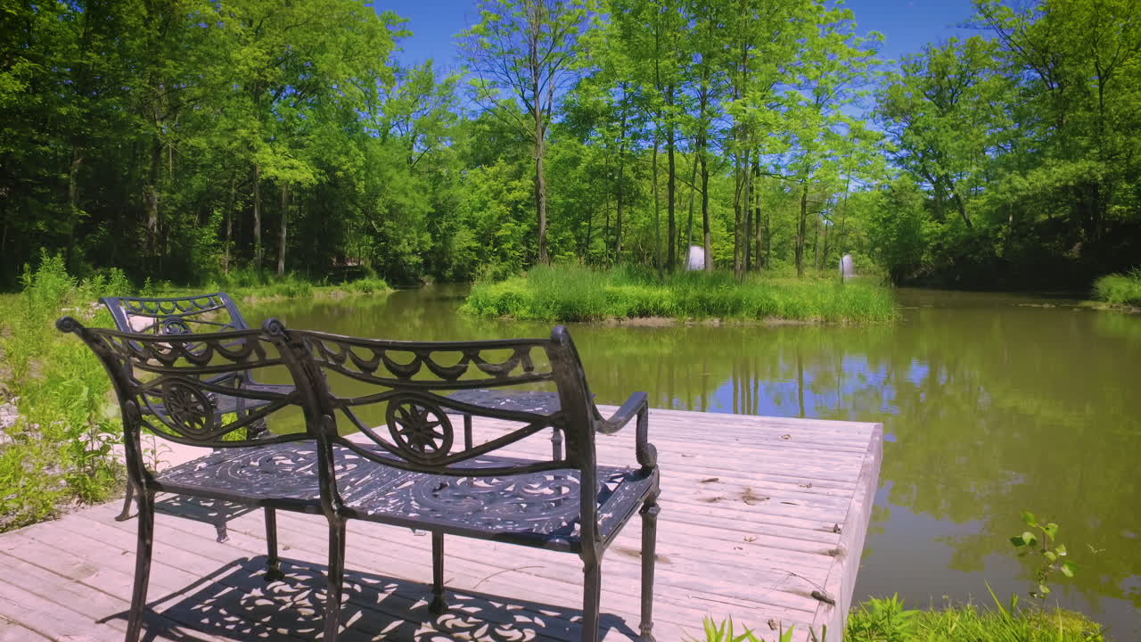 A set of metal benches at the edge of a large pond