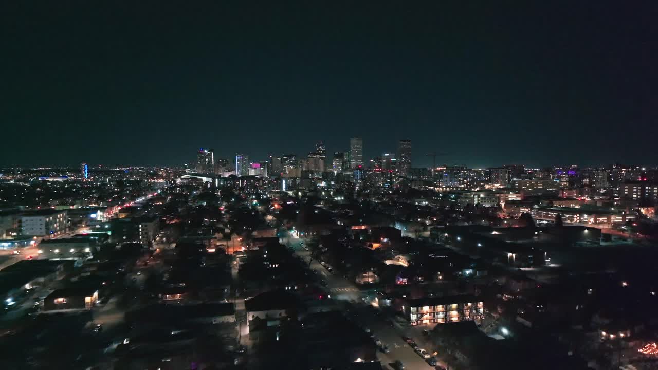 Panoramic aerial view of twinkling city lights in suburb with dense urban buildings in downtown