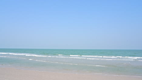 Schäumender-Ozean-Oder-Meereswellen,-Die-An-Einem-Wolkenlosen-Tag-Auf-Einen-Sandstrand-Rollen-Und-Kommen