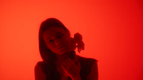 silhouette of a woman holding flowers in red lighting a woman stands in soft red lighting holding flowers the warm hues create a serene and dreamlike atmosphere