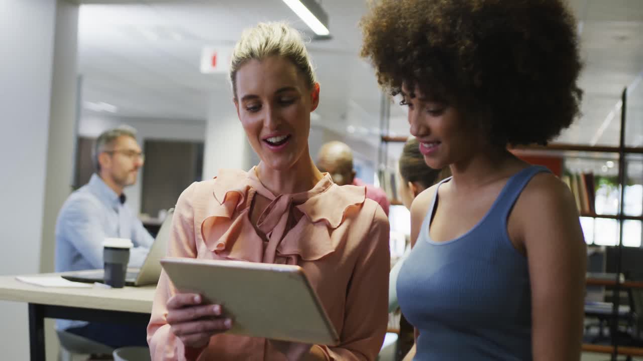 Diverse female business colleagues talking and using tablet