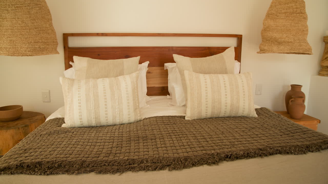 Cozy bedroom with stylish pillows and woven lamp creating warm atmosphere, at home