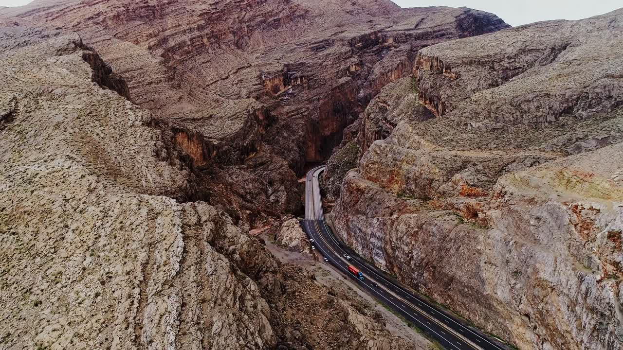 Drone of rugged desert canyon and a road cutting through dramatic rocky cliffs