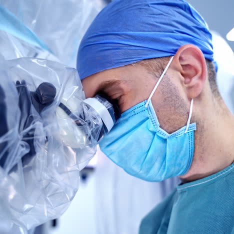 medical specialist performing surgery using modern equipment. profile of surgeon in mask looking into microscope in the operating room.