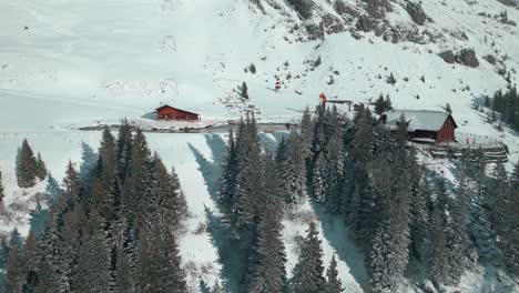 un drone approche d'une cabane près d'un lac artificiel sur une pente enneigée des alpes et de l'arrêt de téléphérique à engelberg, brunni, à bahnen, en suisse