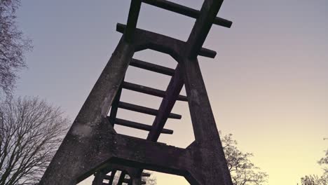 downward panning shot of old concrete rail structure against blueish purple evening sky with trees in background