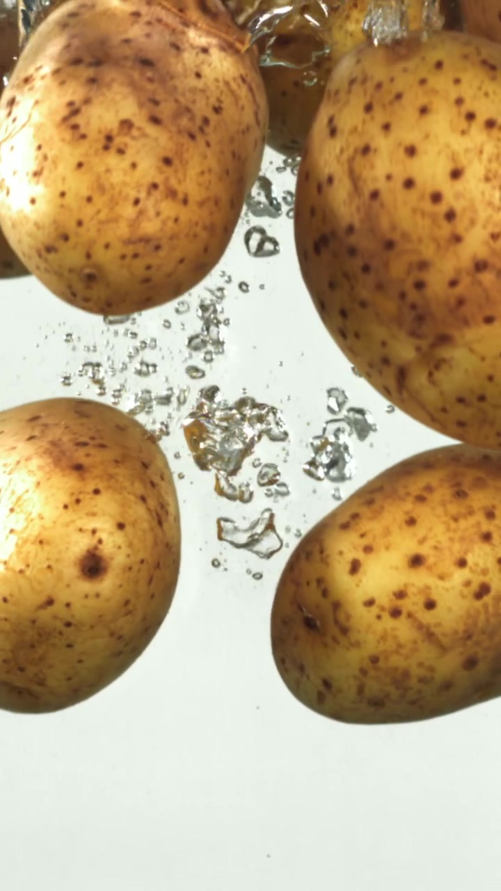 Patate che cadono in acqua limpida al rallentatore