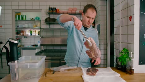 Vista-De-Un-Hombre-Sacando-El-Paquete-De-Bistec-Sellado-Al-Vacío-De-La-Olla-De-Precisión-Sous-Vide