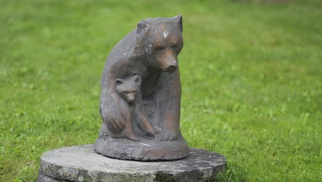 carved wooden statue of the mother bear and her cub in the park of the eveseter hotel surrounded by lush grass and trees