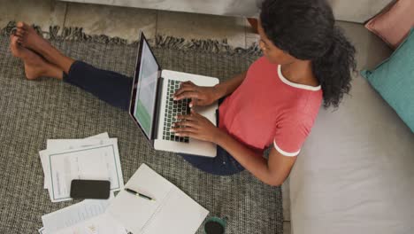 Video-of-happy-african-american-woman-sitting-on-floor-using-laptop