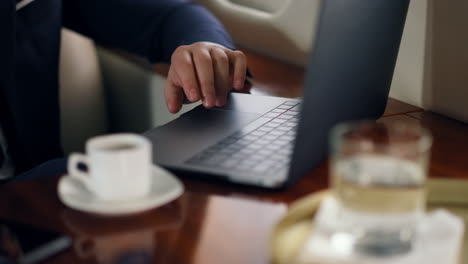 Closeup-hand-tapping-laptop-starting-online-video-conference-on-airplane-trip.