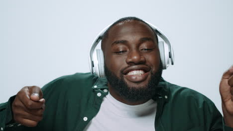 Portrait-of-happy-african-man-dancing-in-headphones-on-grey-background.