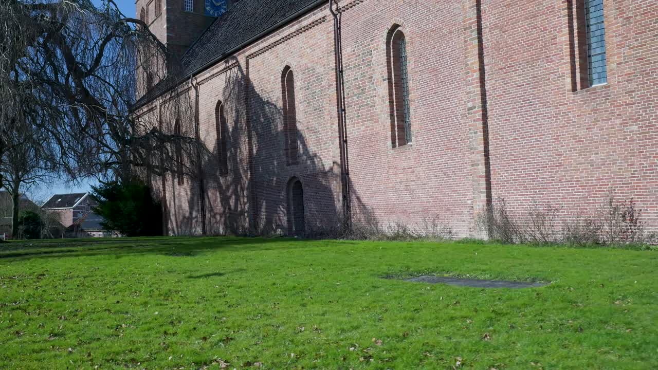Kamerafahrt entlang einer alten Backsteinkirchenmauer an einem sonnigen Tag