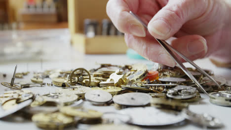 close-up of horologist using tweezers to select a watch part