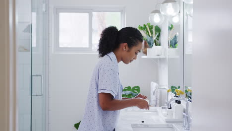 Mujer-En-Pijama-Parada-En-El-Lavabo-Cepillándose-Los-Dientes-En-El-Baño.