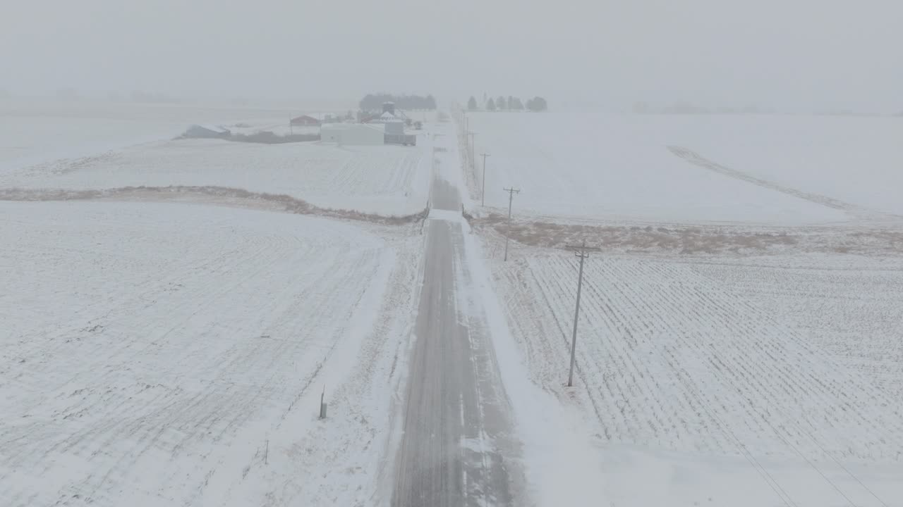 High angle drone view of rural country road during blizzard. White out condition.