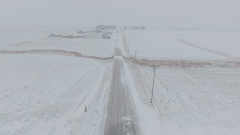 high angle drone view of rural country road during blizzard. white out condition.