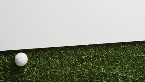 close up of golf ball on grass with white background, copy space, slow motion