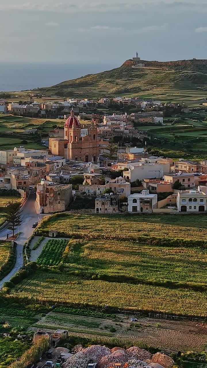 Vista sulla Malta rurale con città, campi e colline sotto un cielo sereno