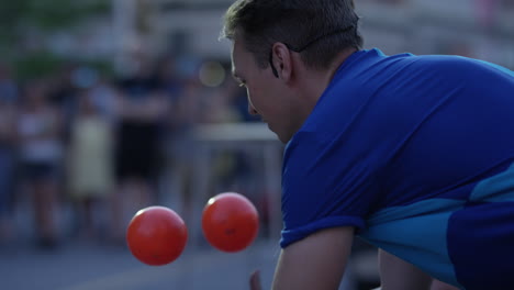 Close-up-slow-motion-juggler-with-orange-balls-in-front-of-crowd