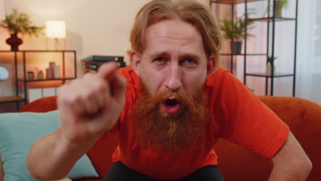 bearded man smiling, pointing to camera, choosing lucky winner, indicating, inviting approve at home