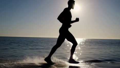 man running on beach at sunset