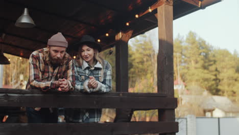 couple standing on wooden terrace outdoors and talking