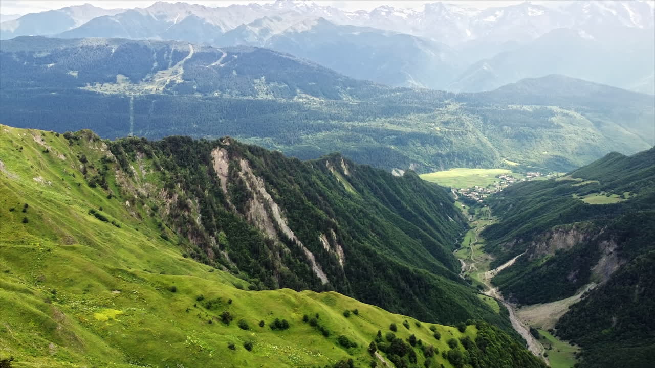 Aerial drone view of nature in Georgia. Caucasus Mountains, greenery, valley, mountain river, village in the distance