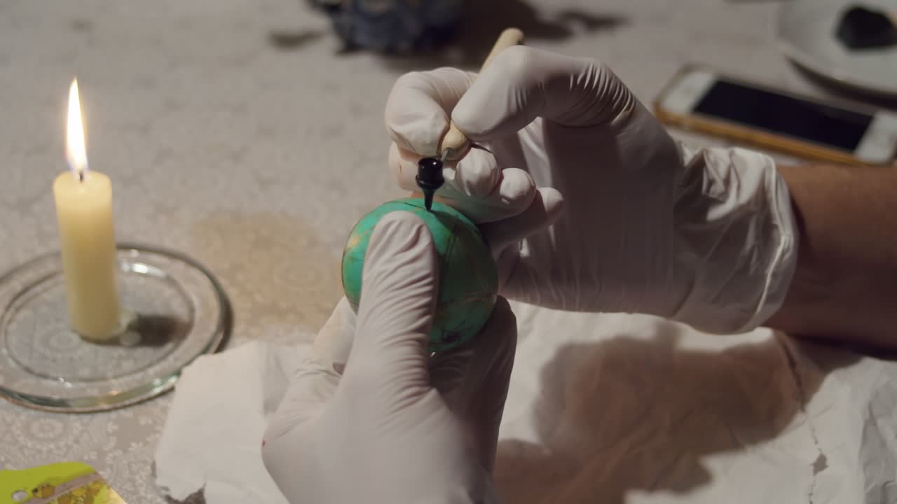 manos femeninas dibujan cuidadosamente un patrón en un huevo de pascua