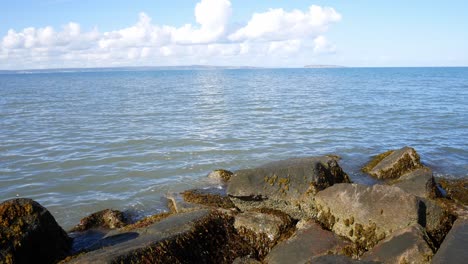 Sonniger-Blauer-Ozeanhorizont-über-Steinkiesstrand-Küstenlinie-Klare-Urlaubsszene