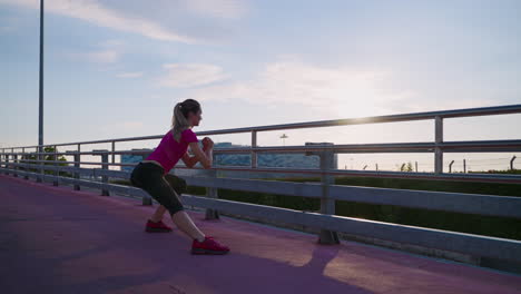 mujer estirándose en un puente al amanecer o al atardecer