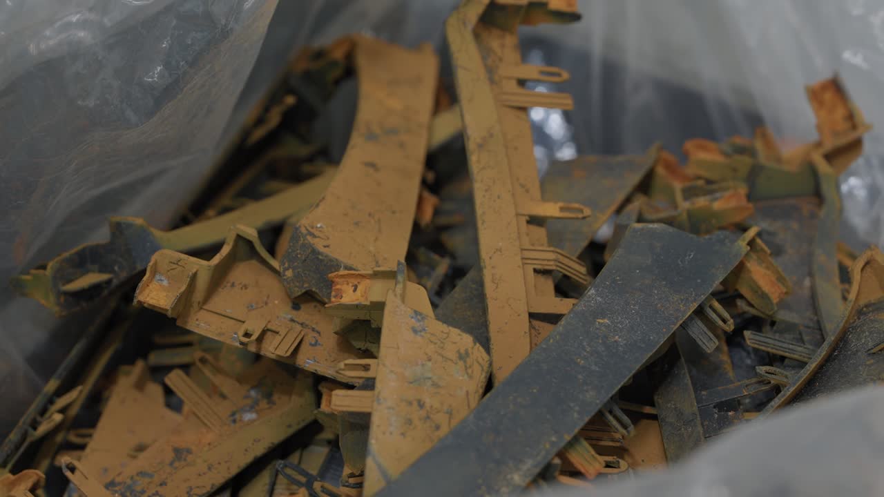 Blandede rustne metalskrotkomponenter og flade strimler indsamlet i plastikpose til genbrugsbehandling