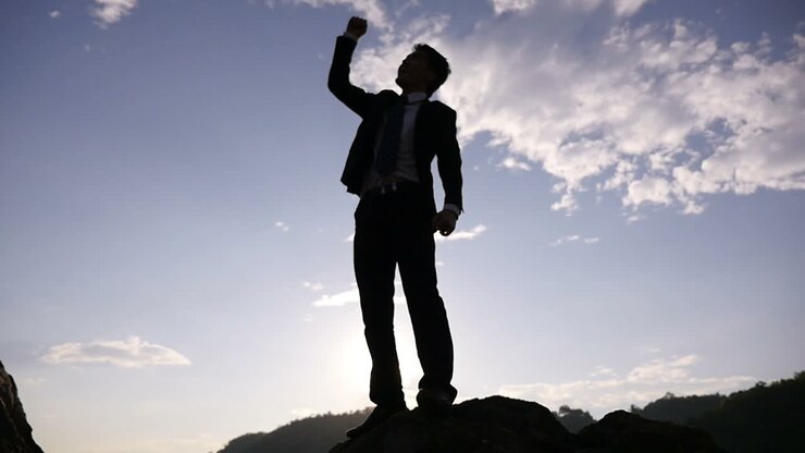 Uomo d'affari che celebra il successo in cima a una montagna