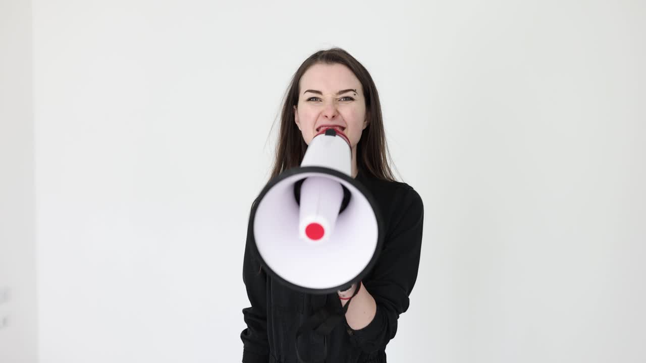 Assertive Young Woman Shouting into a Megaphone on White Background