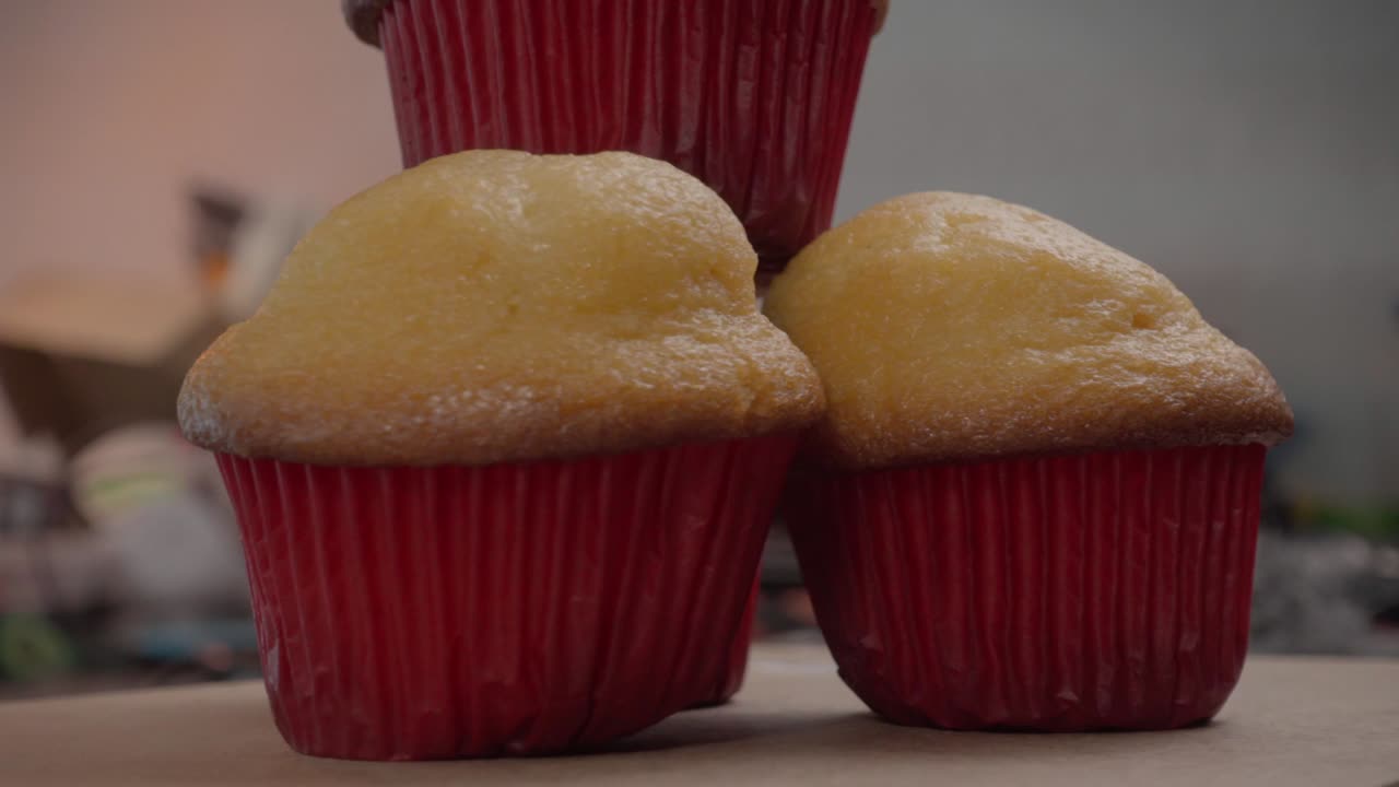 Four delicious vanilla cupcakes with vibrant red wrappers creating a pyramid shape on a rustic wooden rotating surface, beautifully captured in Mexico, exuding sweetness and charm, close up food shot