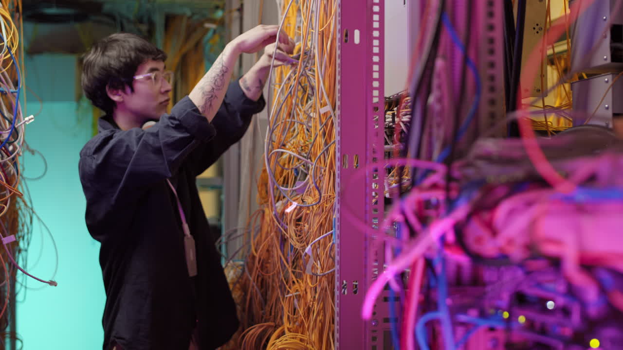 Young IT Technician Connecting Wires in Data Center