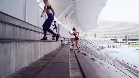 mujeres atletas entrenando saltando escaleras en un estadio