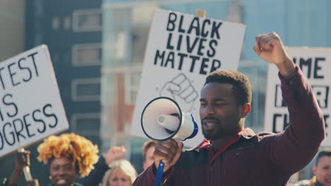 protestors with placards and megaphone on black lives matter demonstration march against racism