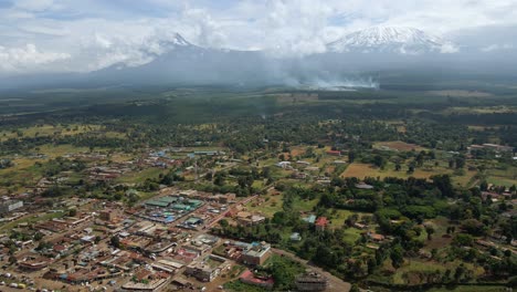 aerial view of a wildland fire under mt kilimanjaro endangering a rural town in kenya - tracking, drone shot