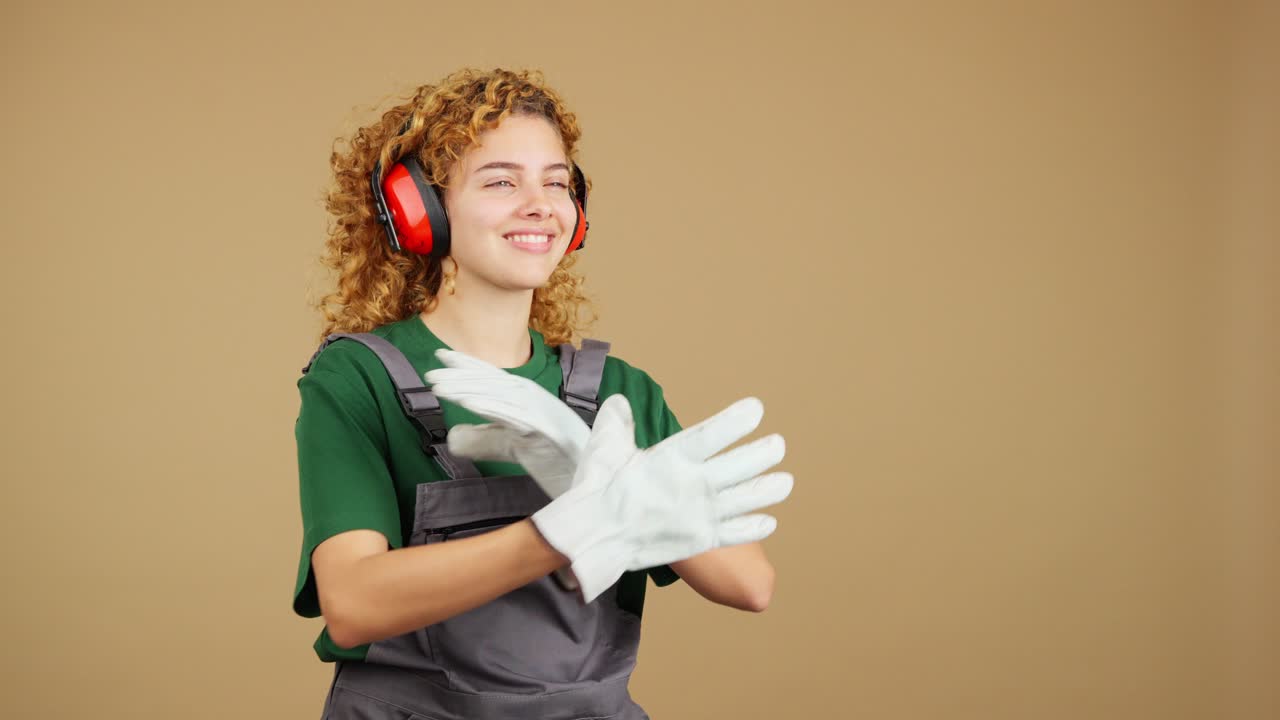 Happy young woman in work overalls and ear protection