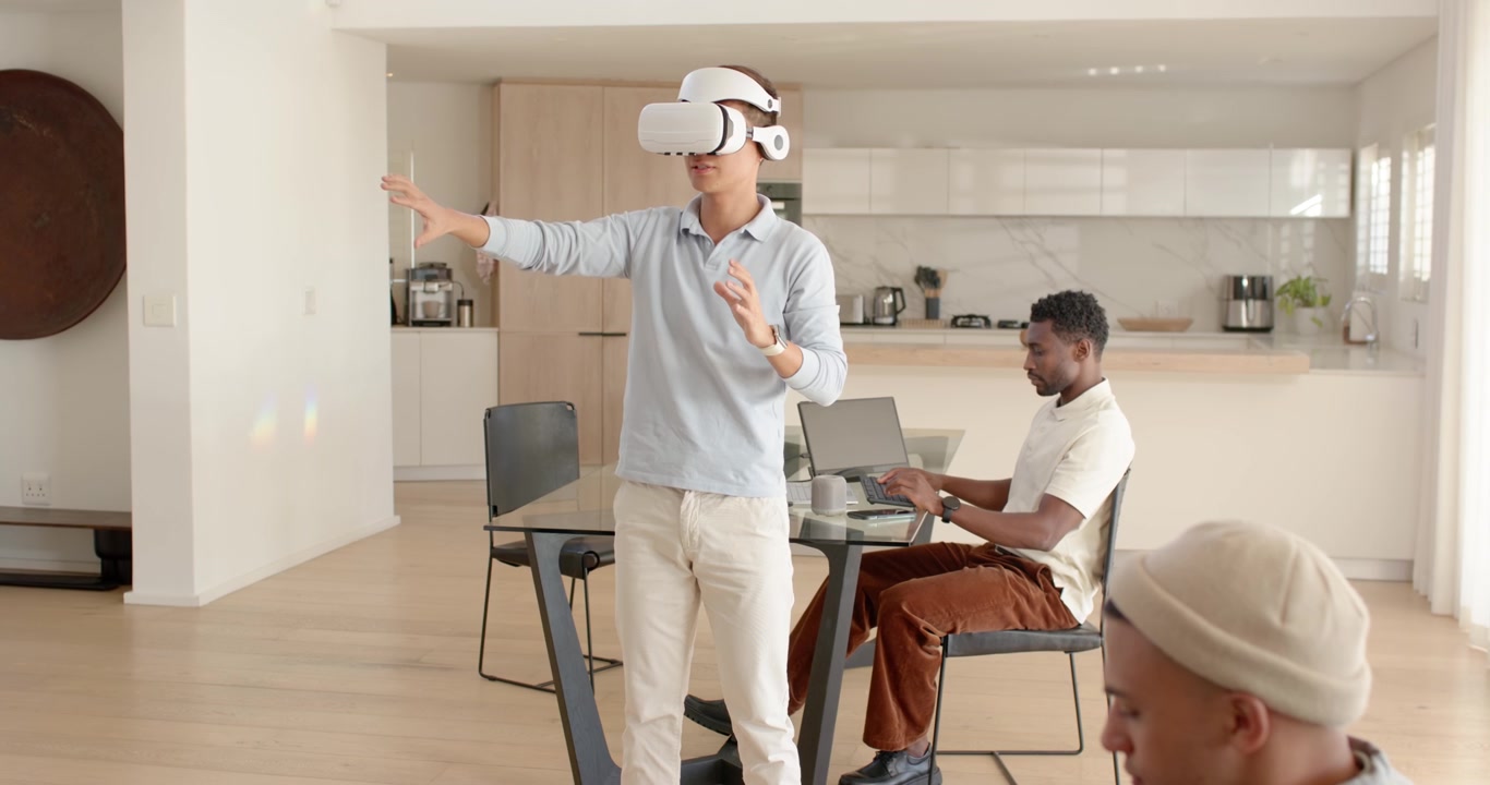 Forskellige mænd ser en asiatisk mand tage et hvidt VR-headset på og udforske derhjemme med bærbar computer og tablet.