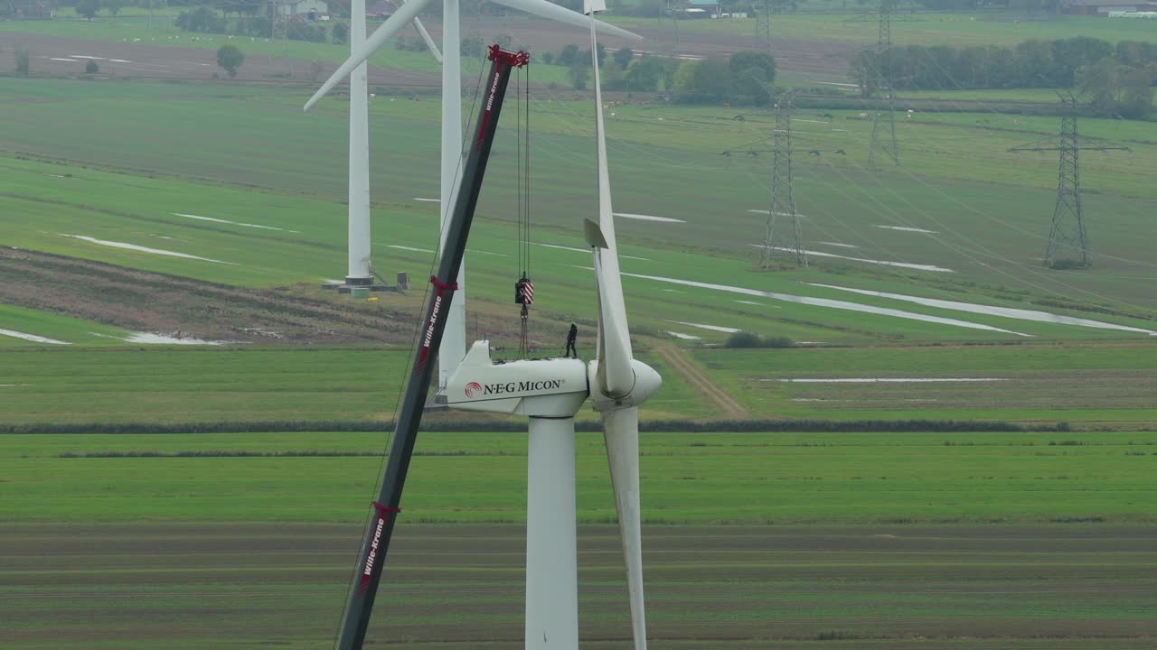 Ripresa con drone di un tecnico che esegue manutenzione in cima a una torre eolica