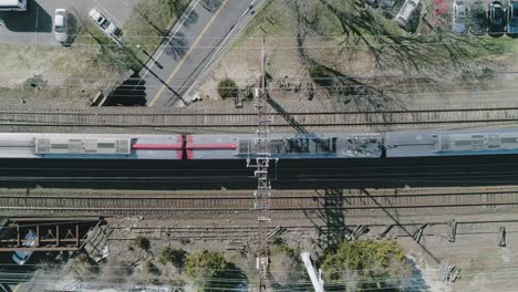 dolly lateral aéreo disparado por encima de las vías del tren con el tren que pasa
