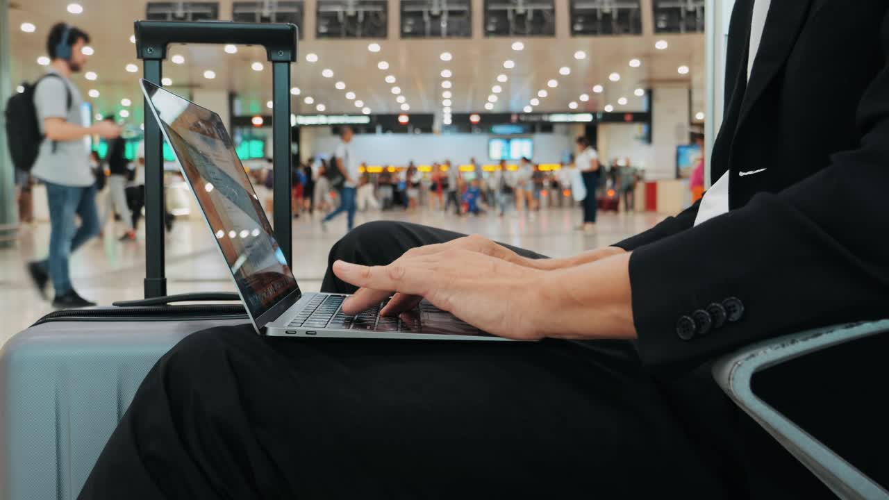 Businessman Uses Laptop, Waiting for a Flight in Airport Terminal or train station, Traveling Entrepreneur Working Online On Computer Sitting in a Boarding Lounge of Airline Hub with Airplanes