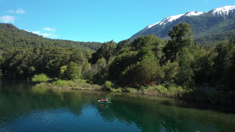 panorámica izquierda de dos hombres pescando con mosca seca en un kayak cerca de la orilla en el lago steffen, montañas en el fondo, patagonia argentina