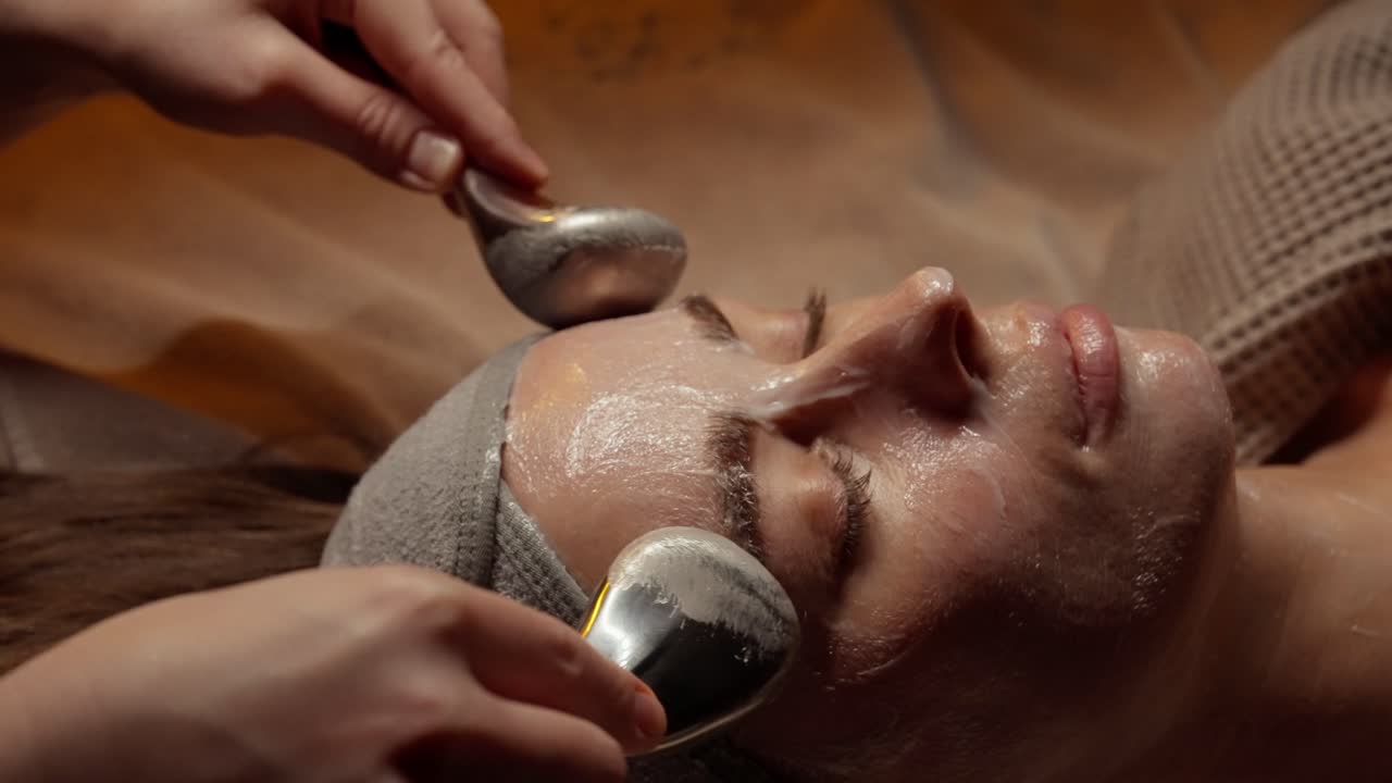 Kvinde får ansigtsbehandling med metalredskaber på et spa