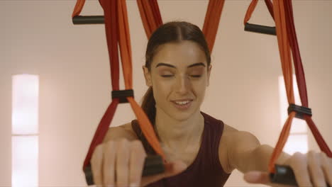 girl exercising with yoga straps in fitness studio. woman practicing yoga inside